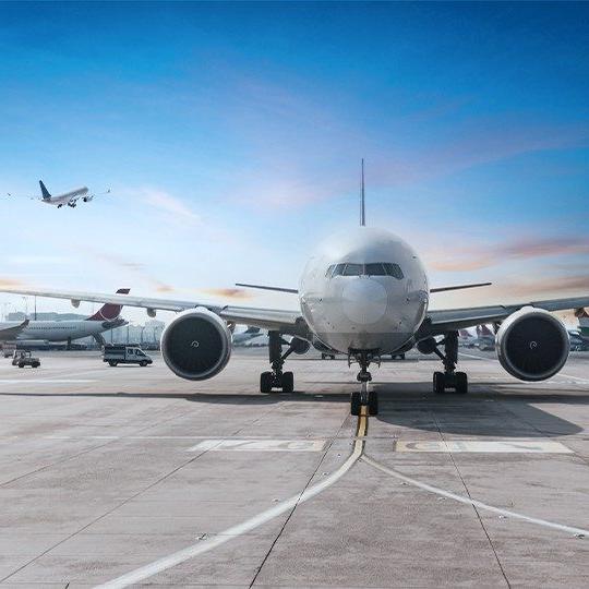 Front-view of a commercial airplane on the runway with a plane taking off in the background